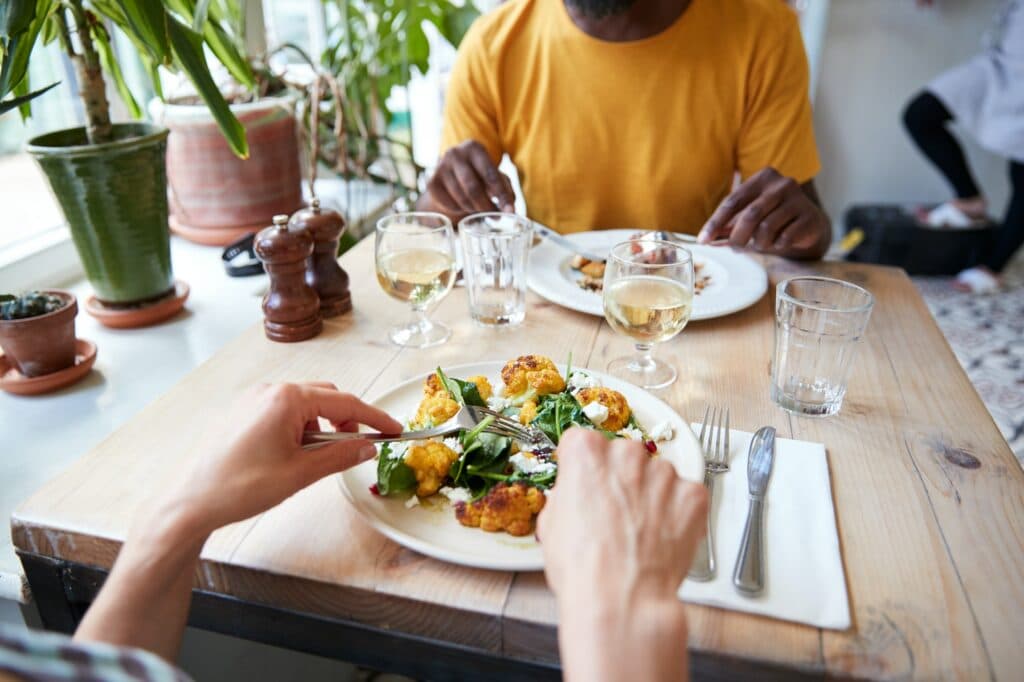 Couple eating at restaurant, over shoulder view, mid section