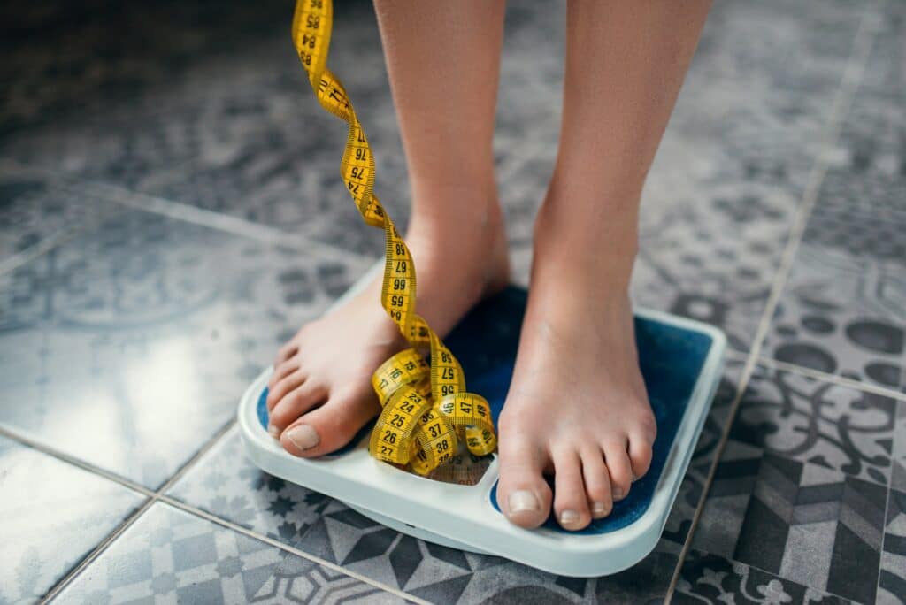 Female feet on the scales closeup, measuring tape